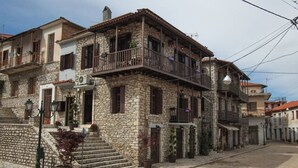 A stone building with a balcony, steps leading to the entrance, and potted plants. - Antique Luxury Suite 75sq.m. (Kalavrita)