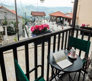 Ein Balkon mit Tisch, Stühlen, einem Buch und einer Tasse.