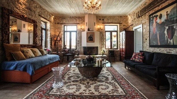 A cozy living room with a fireplace, a sofa, a coffee table, and a chandelier. - Antique Luxury Suite 75sq.m. (Kalavrita)