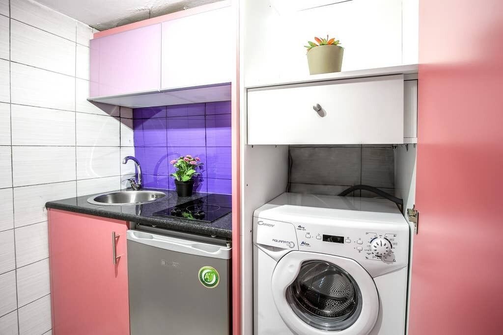 A compact kitchen with a dishwasher, a washing machine, and a small sink.