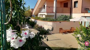 A multi-story building with balconies, outdoor seating, and a garden area. - 30 sqm studio apartment - Kitchenette with living area, sleeping area, bathroom  (Miglianico)
