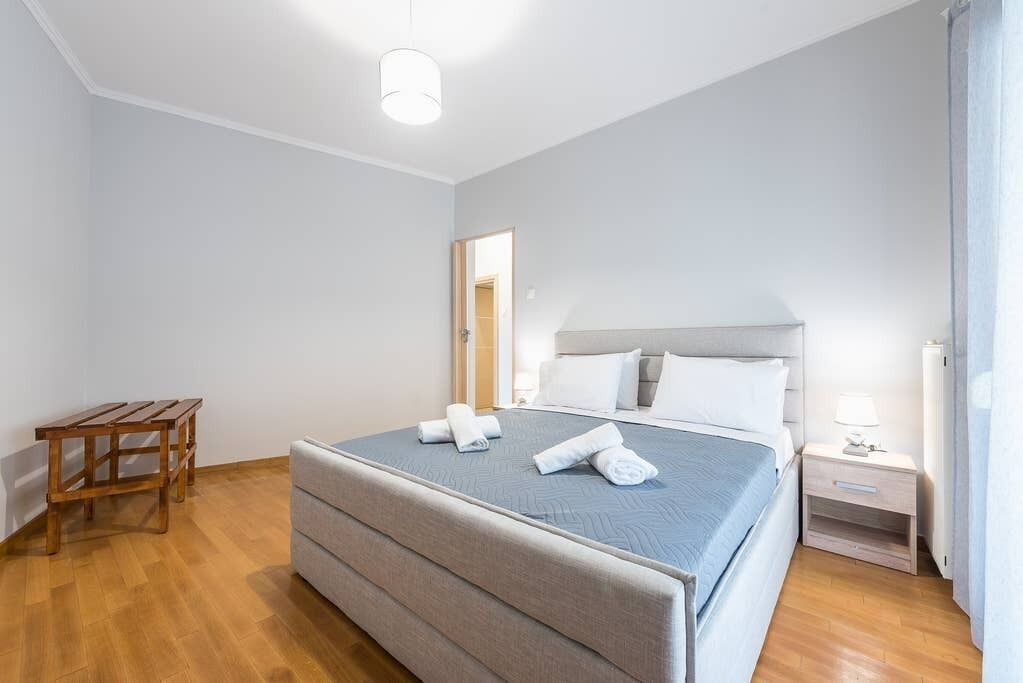 A bedroom with a bed, bedside table, and a small wooden table.