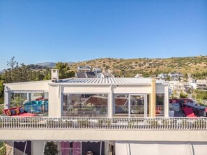 A modern rooftop terrace with glass walls, outdoor seating, and solar panels.