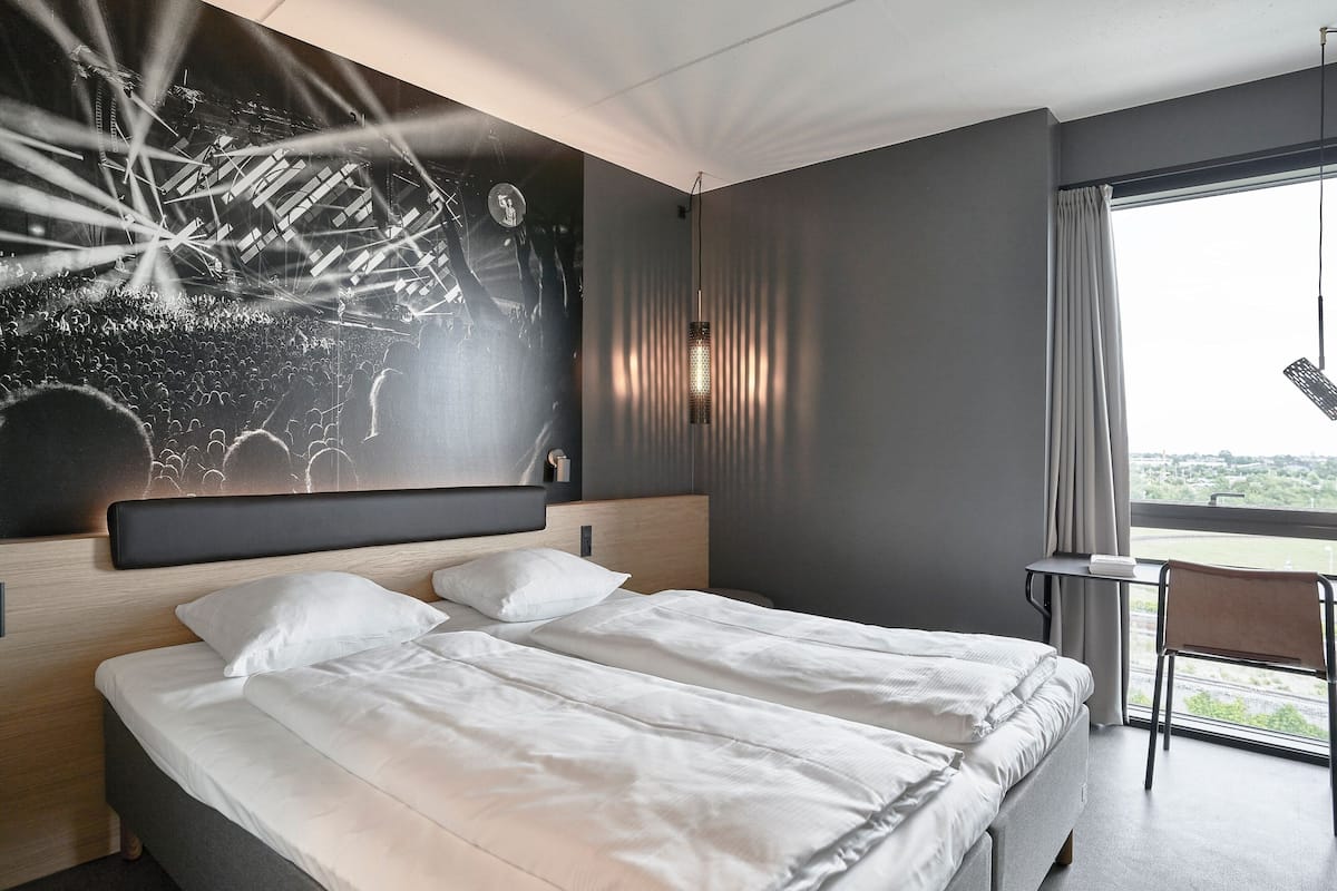 Ein modernes Hotelzimmer mit einem großen Bett, einem Schreibtisch und Blick auf die Stadt.