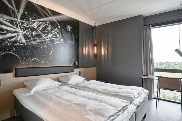 Une chambre d’hôtel moderne avec un grand lit, un bureau et une vue sur la ville.