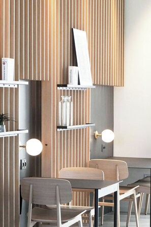 Un interior moderno con listones de madera, un espejo redondo y una mesa con sillas.