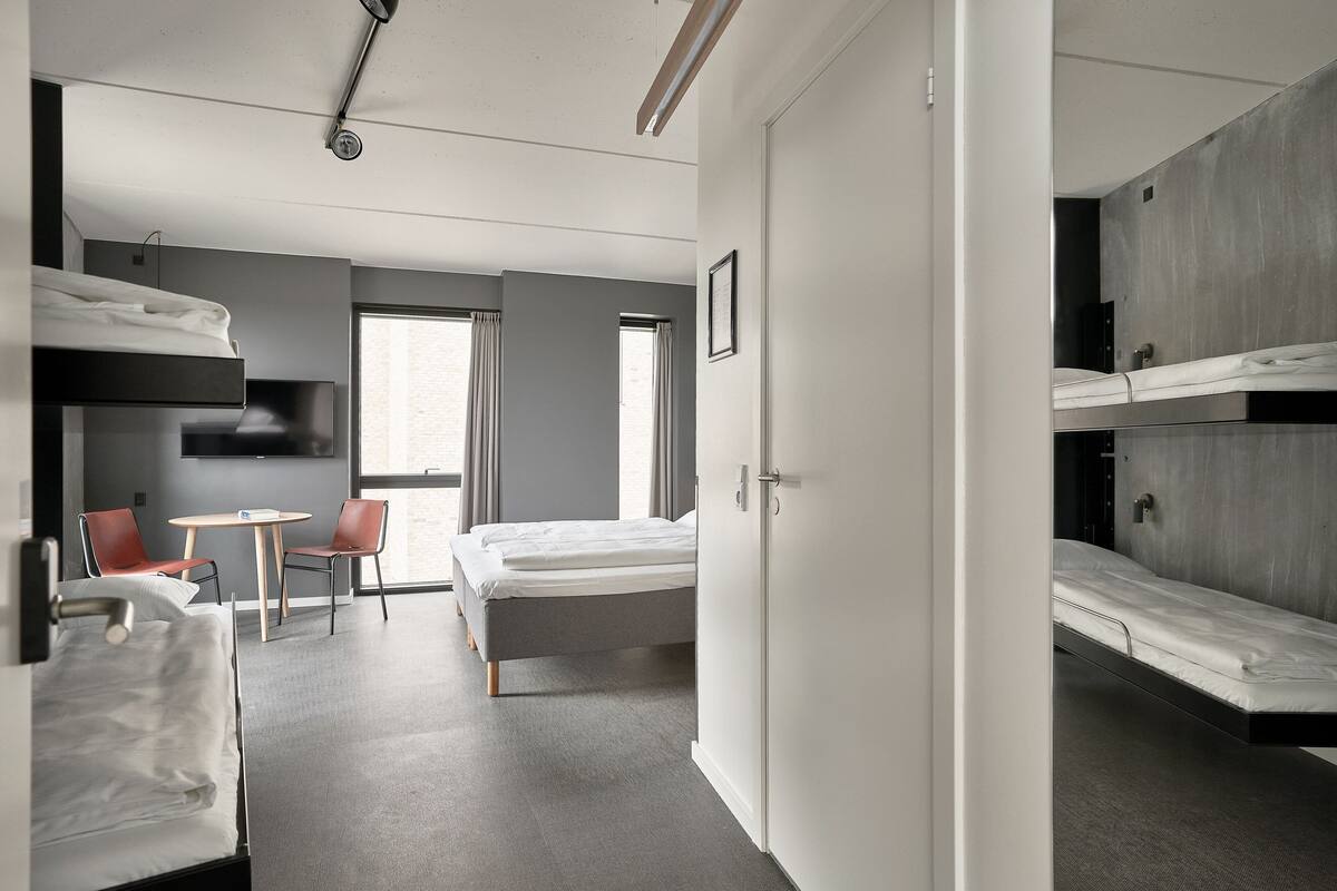 Ein modernes Hotelzimmer mit Etagenbetten, einem Schreibtisch und einem Stuhl.