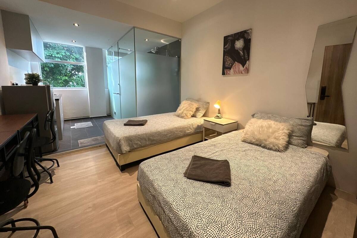 Una camera da letto moderna con due letti, una scrivania e un'ampia finestra.