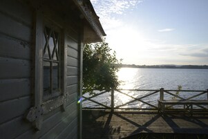 A wooden cabin with a view of a lake.