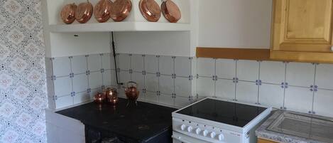 A kitchen with a black stove, a white oven, and a countertop with copper pots.