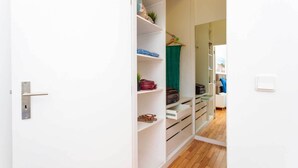Ein begehbarer Kleiderschrank mit offenen Regalen, einer Kleiderstange und einem Spiegel.