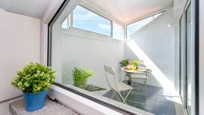 Ein Balkon mit Tisch, Stühlen und Blumentöpfen.