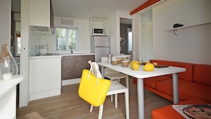 Een moderne keuken met een magnetron, koelkast en eethoek.