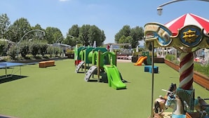 Een speeltuin met groene glijbanen en een draaimolen.