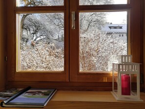 A wooden door with two glass panels, a red candle in a white holder, and a book on a wooden surface.