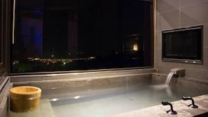 A modern bathroom with a large bathtub, a wooden bucket, and a view of a cityscape at night. - Jia Xin Hot Spring Resort Yangming Shan (New Taipei City)