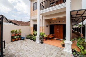 A courtyard with potted plants, a wooden bench, and a building entrance.