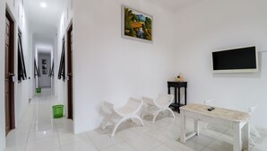Ein Korridor mit weißen Wänden, einem Gemälde, einem Fernseher und einem Tisch mit Stühlen.