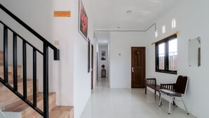 Ein sauberer, gut beleuchteter Flur mit Treppe, einer Bank und einem an der Wand befestigten Stuhl.