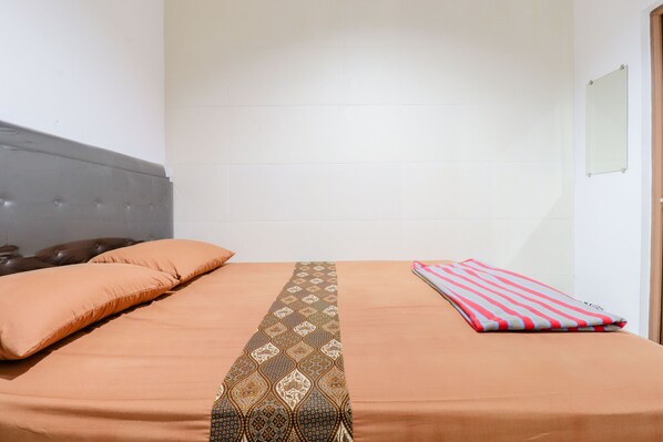 A neatly made bed with a patterned bedspread, a pillow, and a striped blanket.