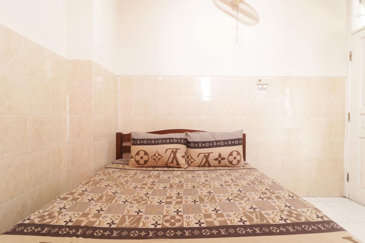 A hotel room with a bed, a patterned bedspread, and a tiled wall.