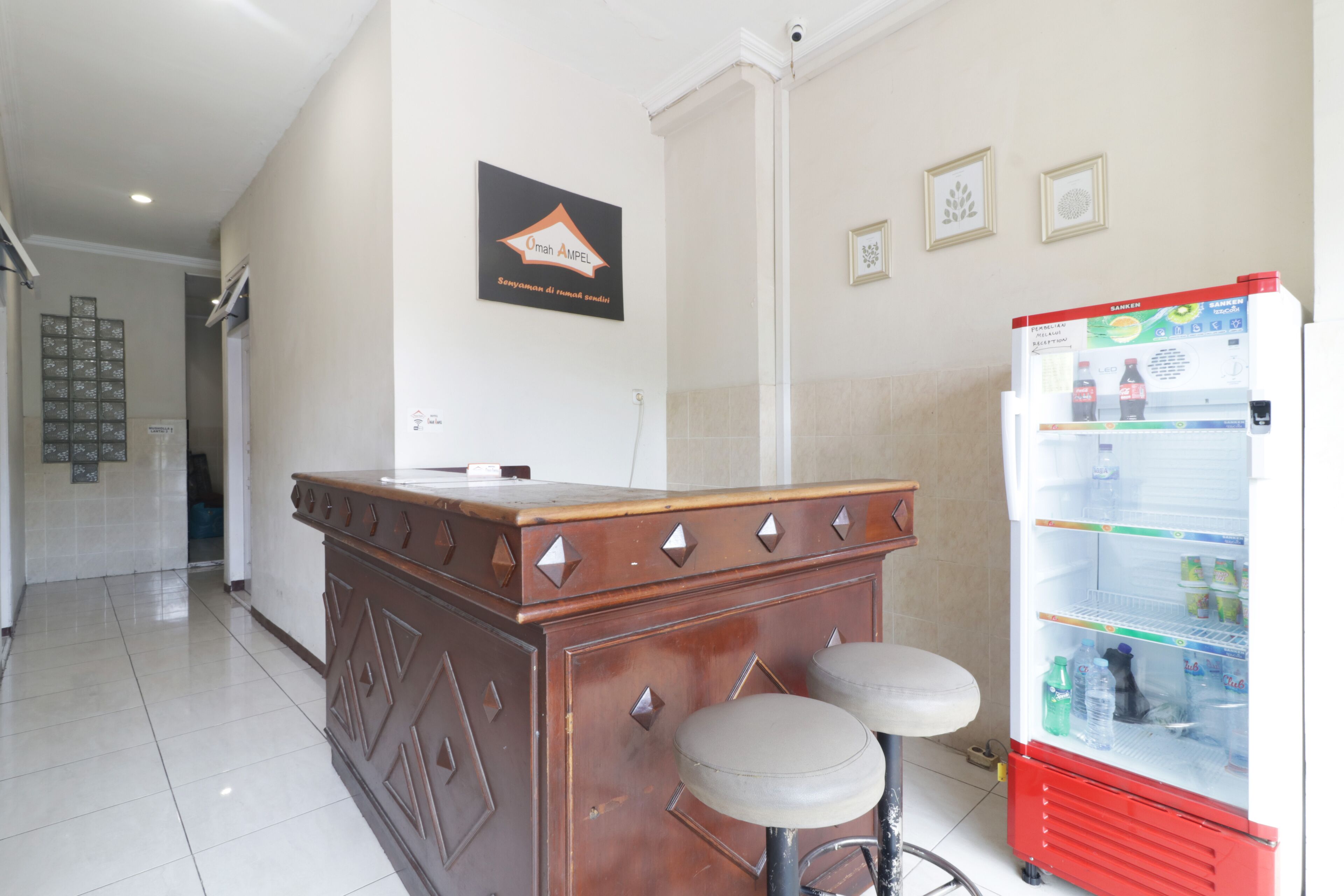 Una cocina con barra de madera, dos taburetes, un refrigerador y un letrero en la pared.