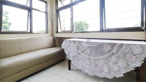 A room with a beige sofa and a table covered with a white lace tablecloth.