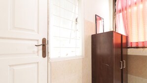 A room with a white door, a dark wooden cabinet, and a window with a grid pattern.