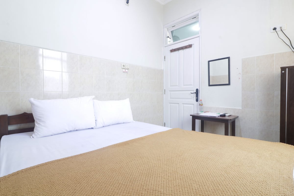 A hotel room with a bed, a bedside table, a mirror, and a wardrobe.