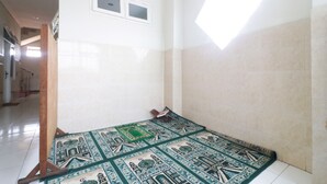 A room with a patterned carpet, a wooden stand, and a window with blinds.