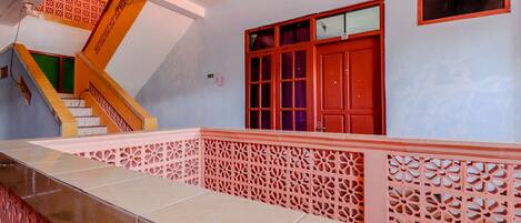 A staircase with a geometric design, a red door, and a patterned railing.