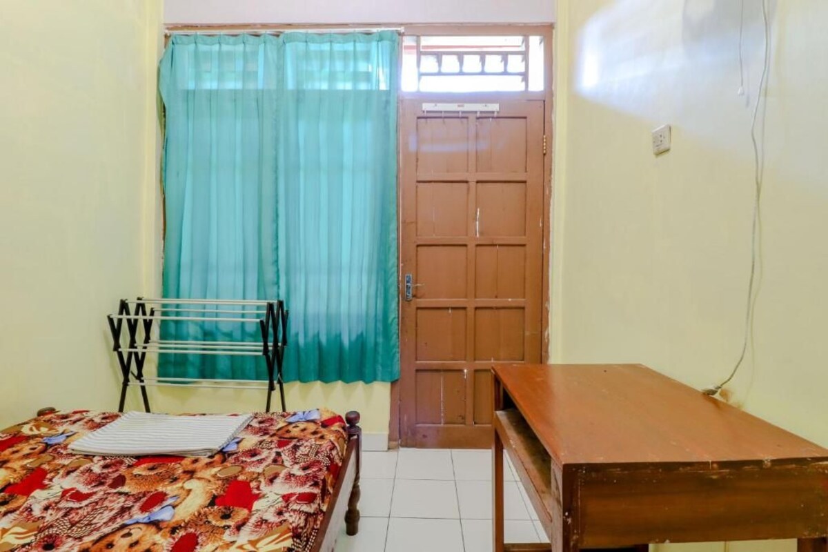 Quarto com cama, uma mesa de madeira, um varal e uma porta com janela.