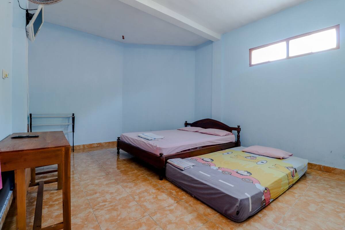 Een kamer met twee bedden, een houten tafel, een stoel en een raam.