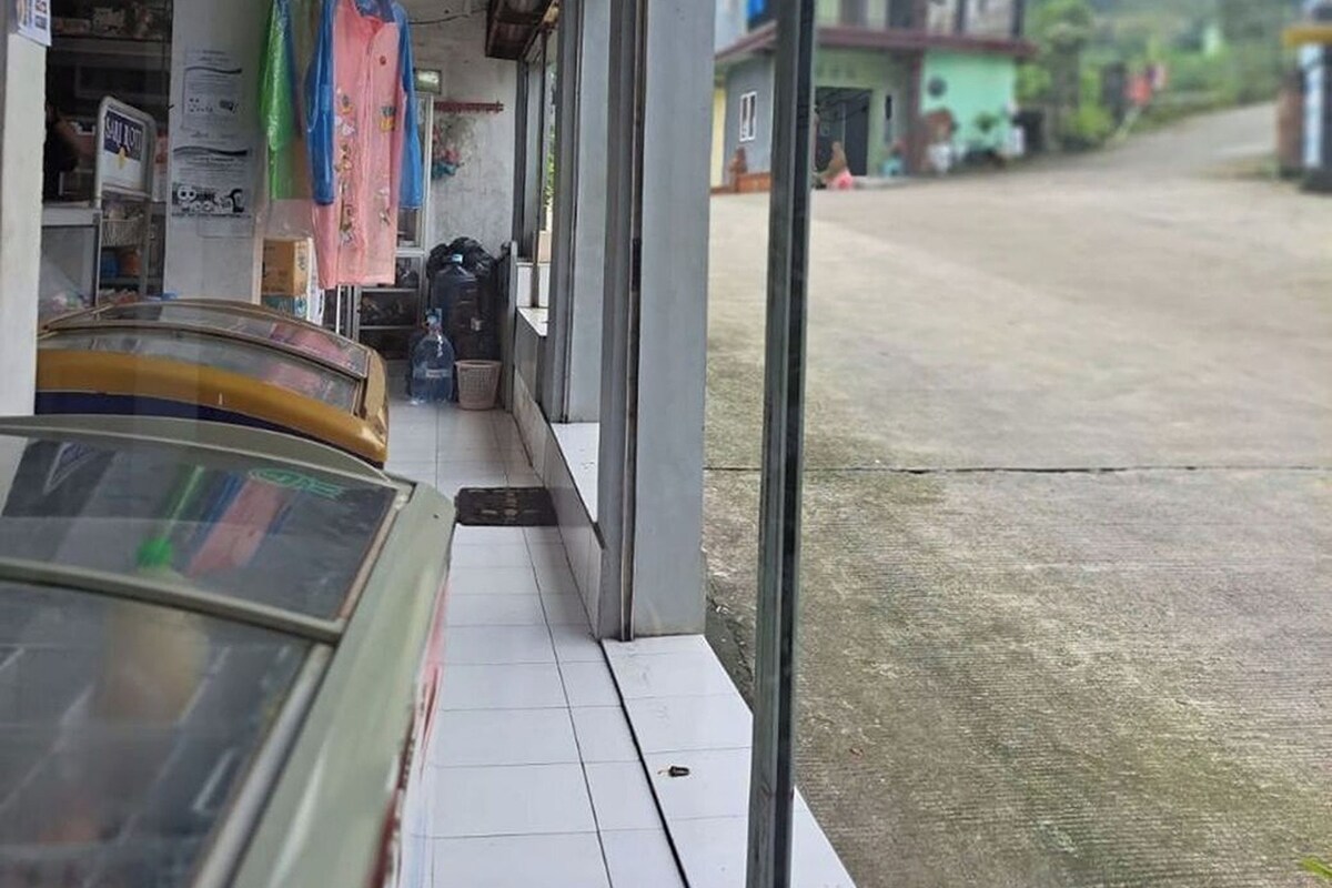 A storefront with a glass front, various items displayed outside, and a view of a road and buildings in the background.