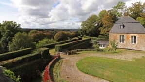 A stone building with a pitched roof, surrounded by a well-maintained garden with hedges and a gravel path. - Chaplain's House: Charm in Swiss Normandy, Pets Allowed (Rabodanges)