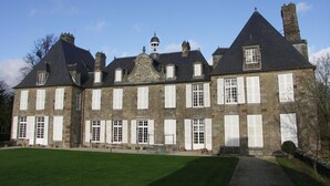 A large, historic stone building with multiple chimneys, a central dome, and symmetrical windows. - Chaplain's House: Charm in Swiss Normandy, Pets Allowed (Rabodanges)