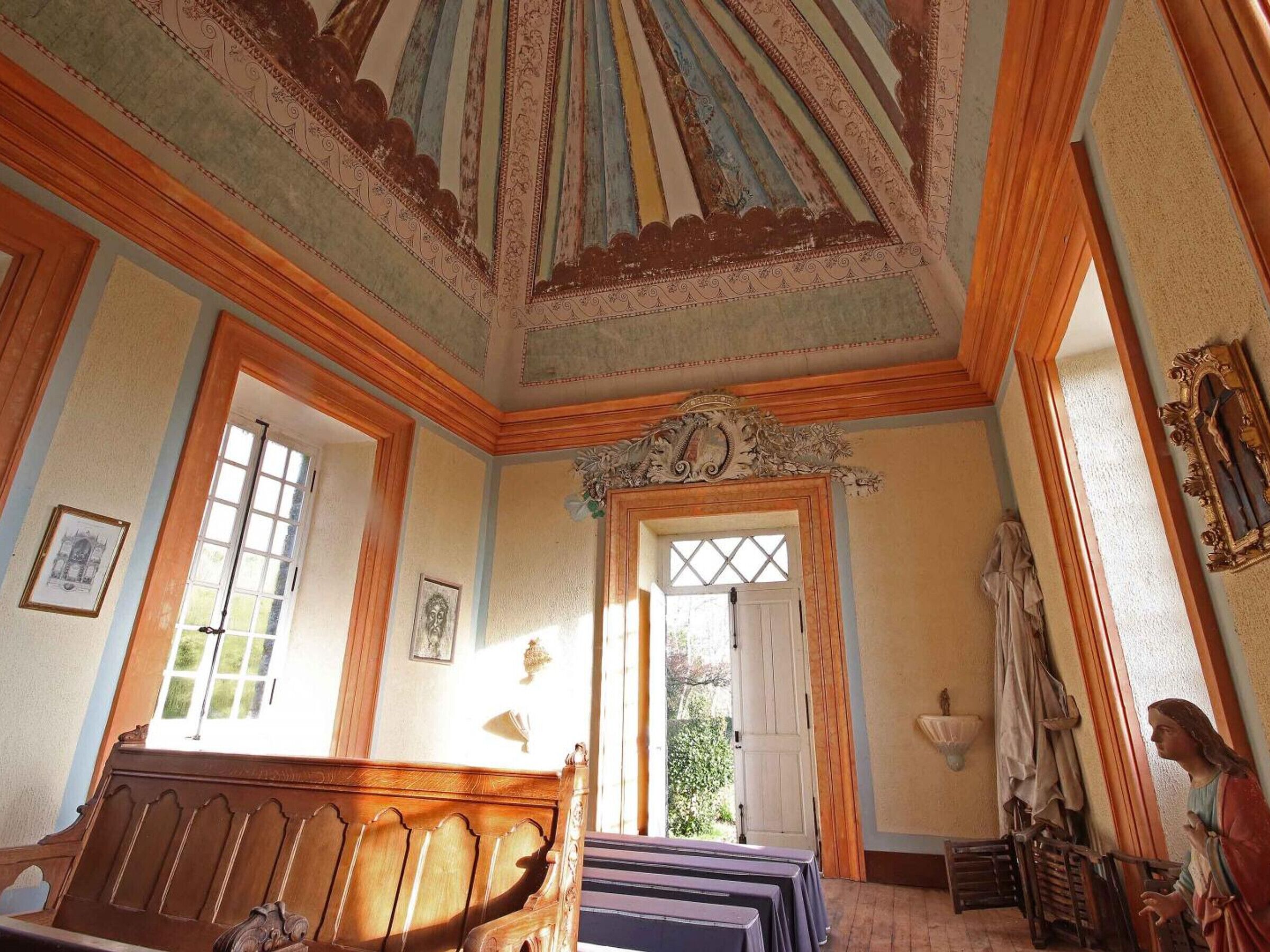 A room with a wooden bench, a large window, and a statue.