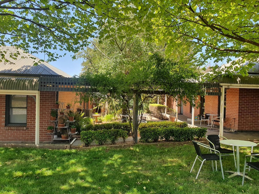 A patio area with a brick building, a pergola, and outdoor seating.