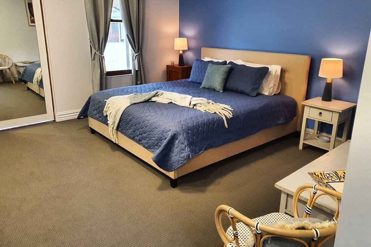 A hotel room with a large bed, two bedside tables with lamps, a chair, and a mirror.