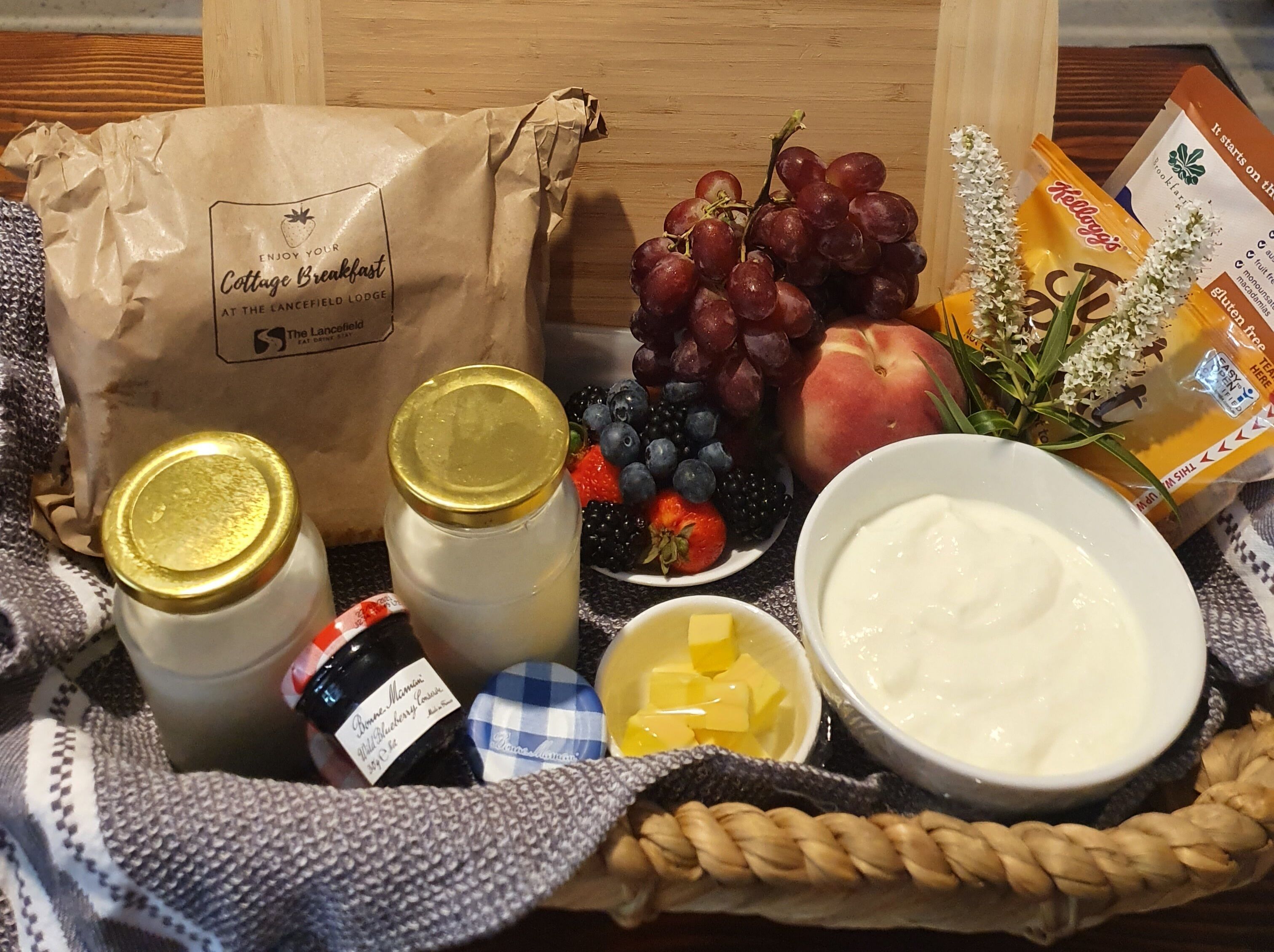 A breakfast spread with fruits, yogurt, honey, and a bag from Cottage Breakfast.