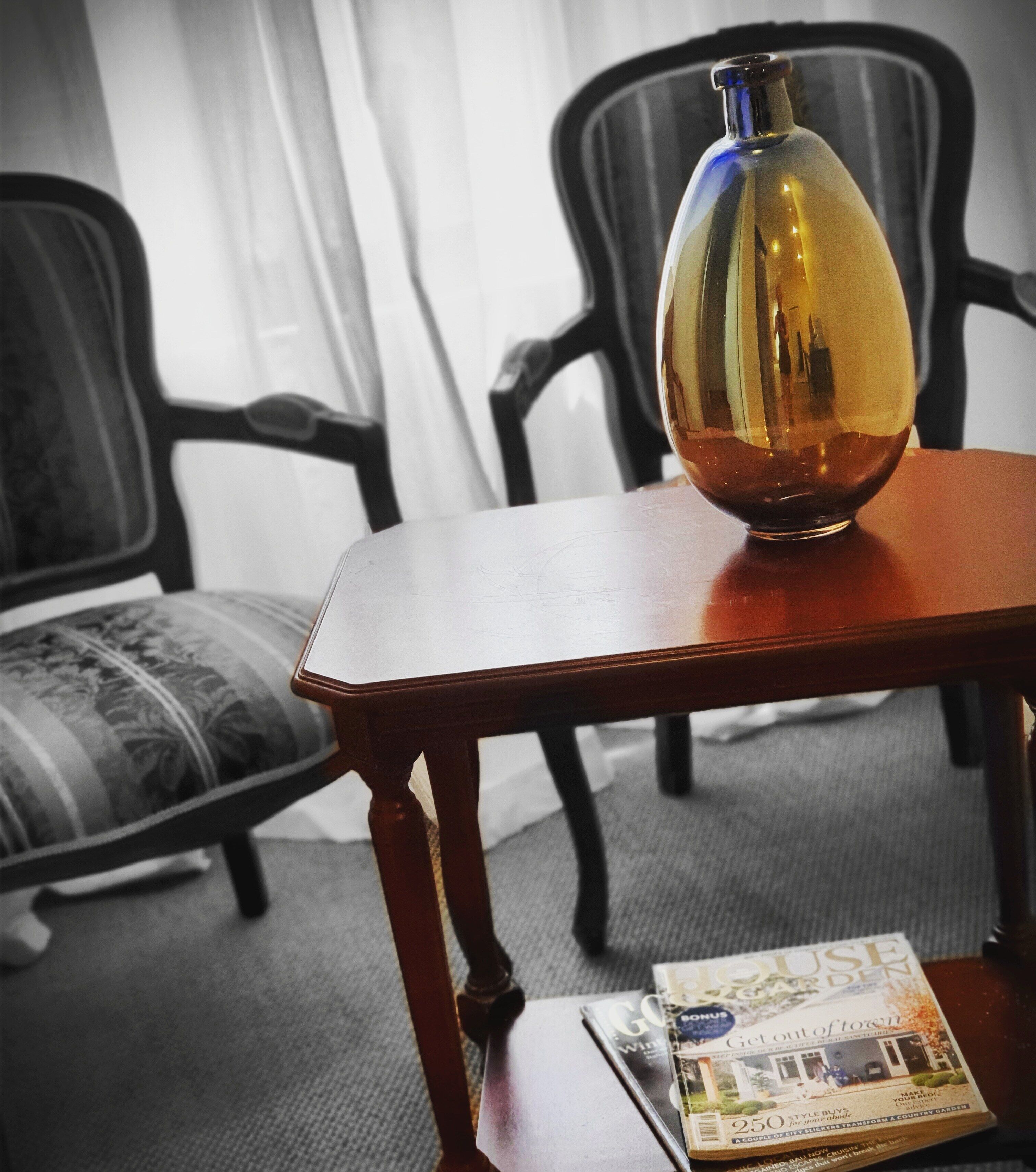 Una habitación con una mesa de madera, un jarrón y una revista.