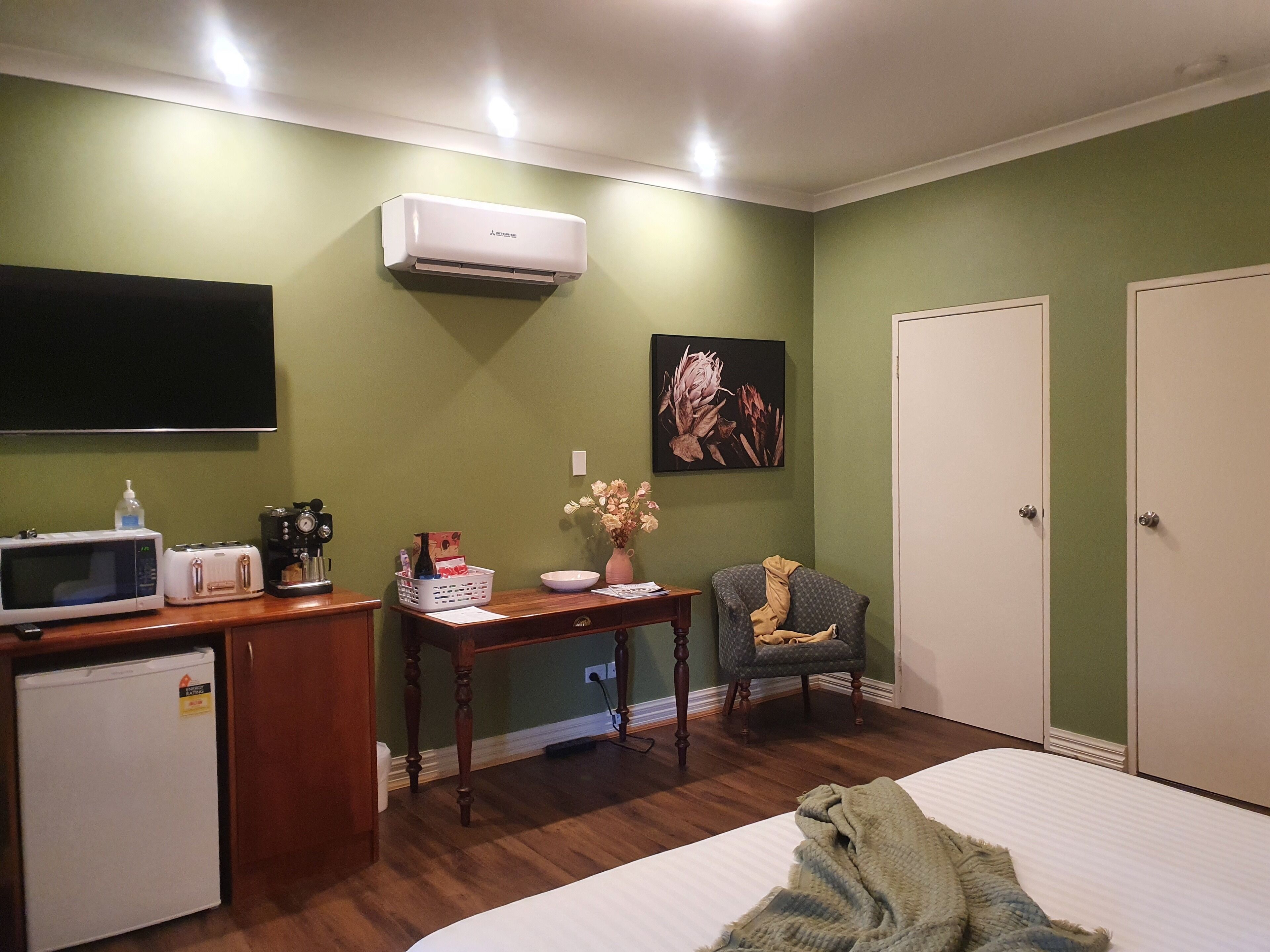 Une chambre comprenant un lit, un bureau avec un ordinateur, un four à micro-ondes, un réfrigérateur, un climatiseur et une chaise.