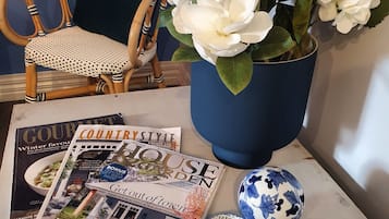 A magazine spread with a wicker chair, a vase of white flowers, and decorative bowls.