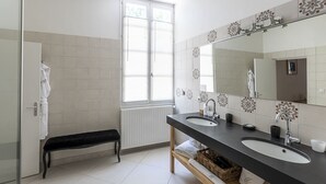 Moderni kylpyhuone, jossa on kaksi pesuallasta, suuri peili ja penkki.