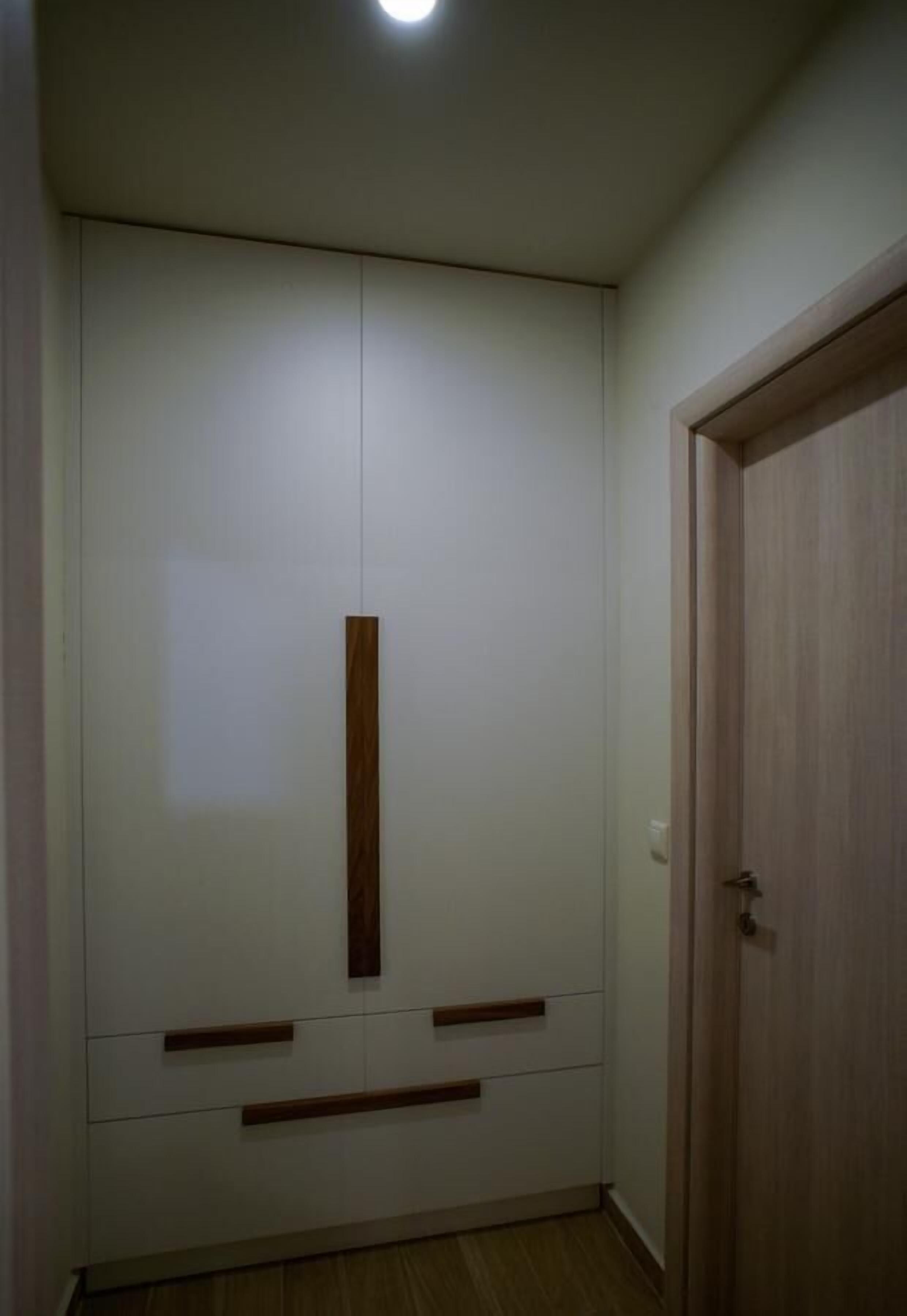 Una habitación con un armario grande, una puerta de madera y una lámpara en el techo.