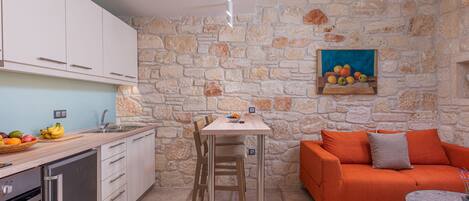 A compact kitchen with a stone wall, a dining table, and a sofa.