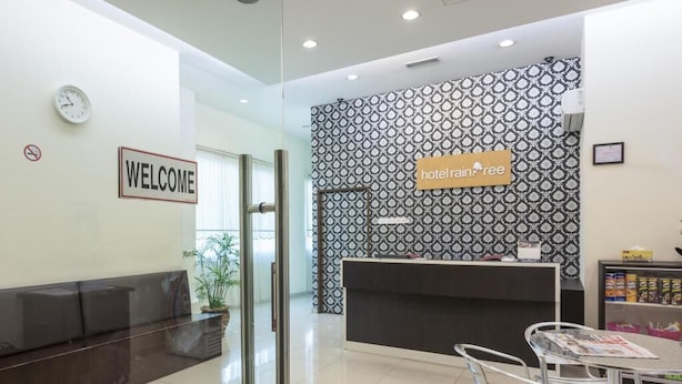 A hotel reception area with a 'WELCOME' sign, a reception desk, a seating area, and a patterned wall. - Raintree Hotel (Kuala Lumpur)