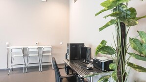 A small office with a desk, two chairs, a computer, and a large plant. - Raintree Hotel (Kuala Lumpur)