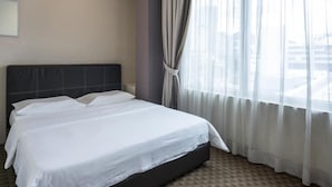 A hotel room with a large bed, a view of the city through sheer curtains, and a modern design. - Raintree Hotel (Kuala Lumpur)