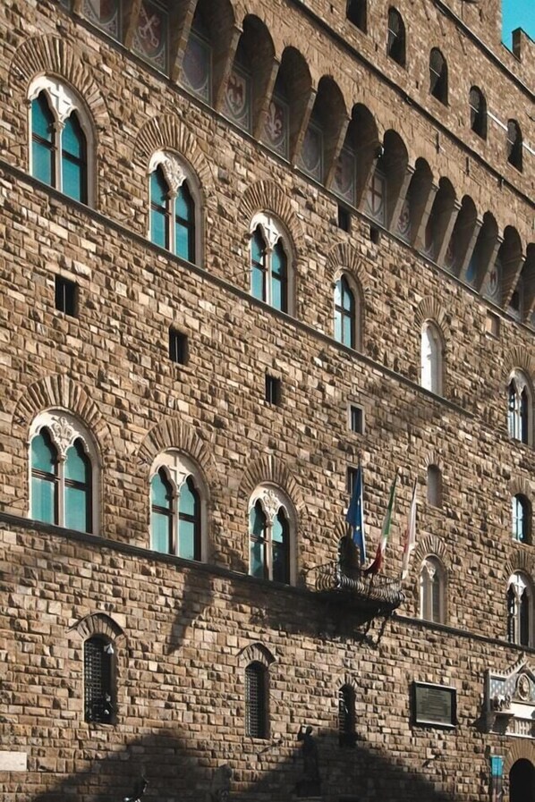 A historic stone building with multiple arched windows and a central flagpole.
